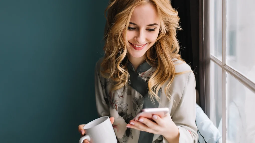 Femme qui utilise un téléphone intelligent pour chercher du contenu sur le web, illustrant pourquoi les clics ne suffisent plus pour mesurer la performance web.