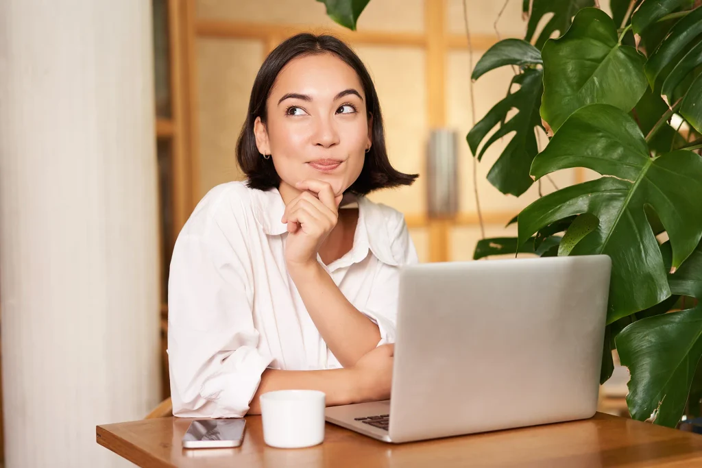 Femme réfléchissant devant son ordinateur portable aux questions de ses clients